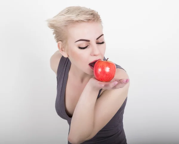 Hermosa chica joven en un vestido gris con manzana que le recuerda a mantener una dieta saludable — Foto de Stock