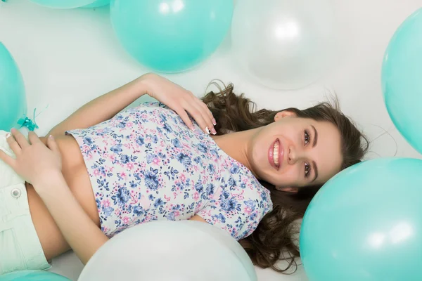 Όμορφη σγουρά κορίτσι σε πολύχρωμα κορυφή, λευκό σορτσάκι και φωτεινά παπούτσια παιχνίδι με μπαλόνια — Φωτογραφία Αρχείου