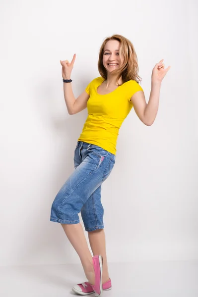 Красива блондинка дівчина в жовту сорочку, блакитні Шаровари показує жест Вікторія — стокове фото