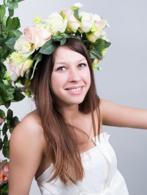 Küçük beyaz elbiseli, salıncakta salıncak sallanan, halatla sarmaş dolaş sarmaşık sarmaşık sarmaşık sarmaşığı. Kafasında çiçek çelengi olan kız. bahar havası