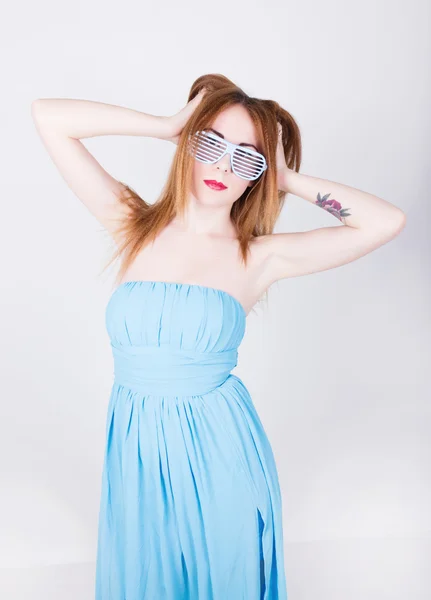 女孩在蓝色礼服和太阳镜在迪斯科的风格，举起他的手到顶部，触摸她的头发 — 图库照片