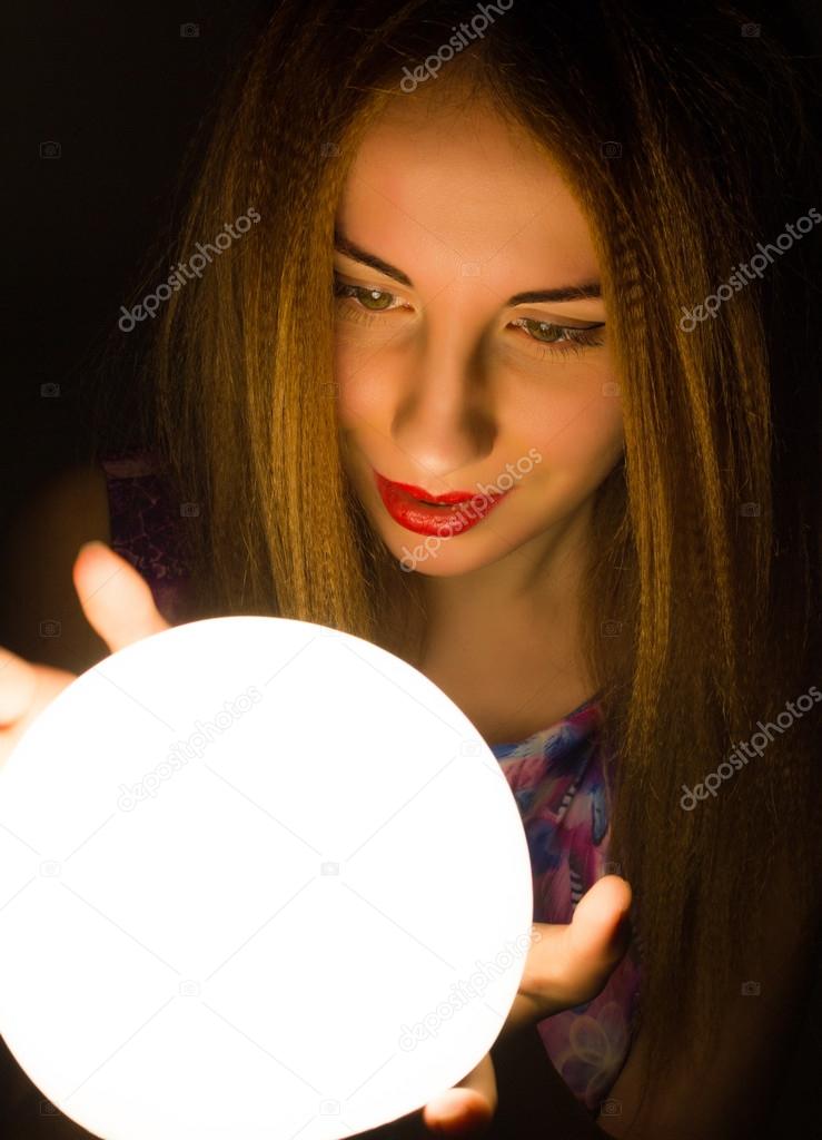 Magnificent Redhead fortune teller holding crystal ball. beautiful woman tries to look into the future