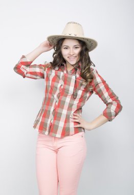 beautiful curly girl in pink pants, a plaid shirt and cowboy hat.