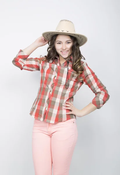 Beautiful curly girl in pink pants, a plaid shirt and cowboy hat. — Φωτογραφία Αρχείου