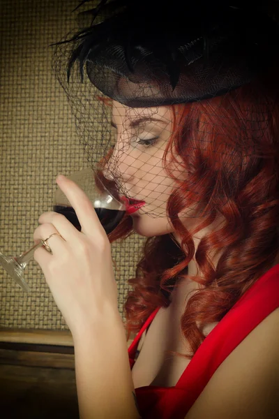 Крупный план портрета Элегантной молодой рыжей женщины в красном платье, выпившей бокал красного вина — стоковое фото