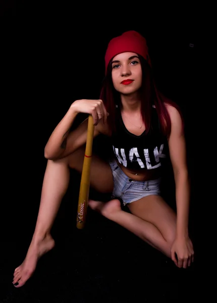 Joven adolescente girlin una gorra de punto rosa, posando con un bate de béisbol. juego de luces y sombras —  Fotos de Stock