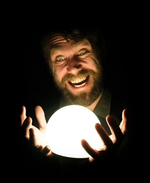 Close-up of a bearded man expresses various emotions on a black background, holding a lamp in front of himsalf — Stock Photo, Image