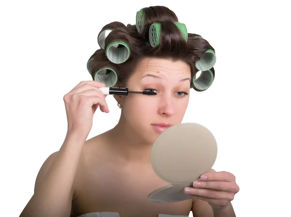 Fiatal nő hajcsavaróval a fején teszi magát smink. elszigetelt fehér háttér — Stock Fotó