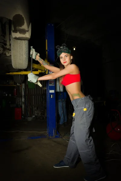 Vackra unga kvinnliga mekaniker inspekterande bil i auto reparera butik. Sexig mekaniker — Stockfoto