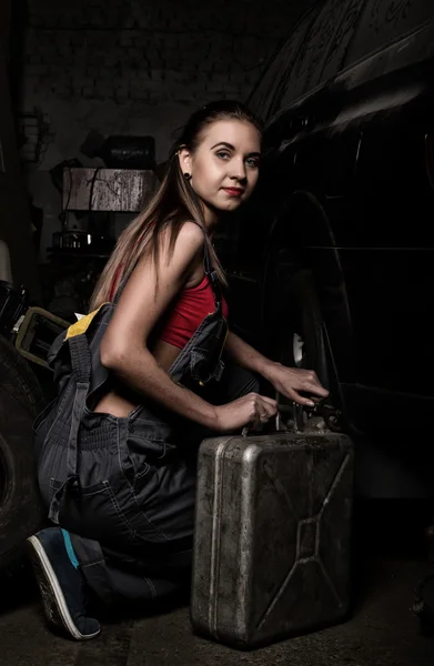 Sexy meisje monteur zittend naast de machine en het houden van een kan van benzine. kleurloze Life concept — Stockfoto