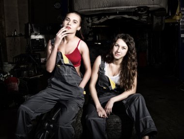 yorgun mekaniği seksi kızlar lastikler üzerinde bir araba tamir, kızlar duman yığını üzerinde oturuyor. renksiz hayat kavramı