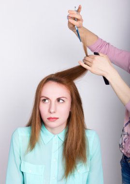 Salonda güzel genç kızıl saçlı model, kuaför bir saç modeli yok. makas ile saç uçları kırpar