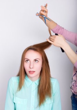 Salonda güzel genç kızıl saçlı model, kuaför bir saç modeli yok. makas ile saç uçları kırpar