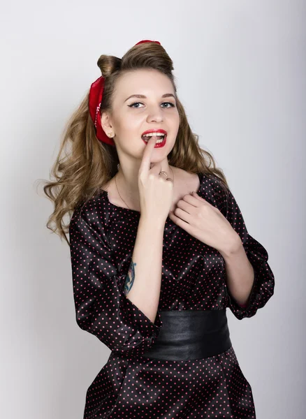 Sexy young blond with long curly hair in a black polka-dot dress, put her index finger to her red lips — 스톡 사진