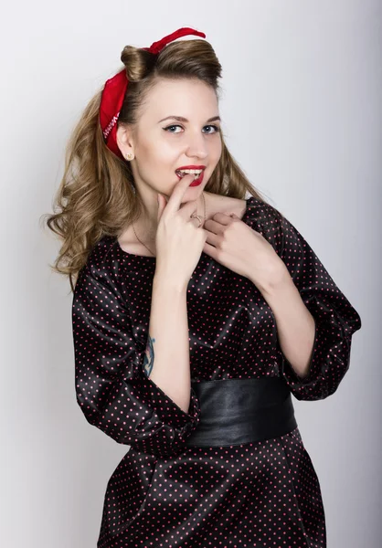 Sexy joven rubia con el pelo largo y rizado en un vestido de lunares negro, poner su dedo índice a sus labios rojos — Foto de Stock