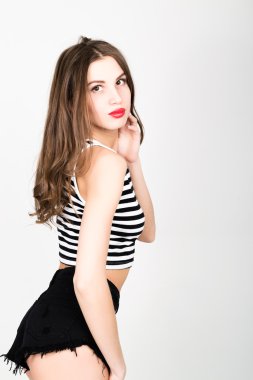 close-up beautiful slim woman in black shorts and a striped top is in multi-colored shoes, brunette posing