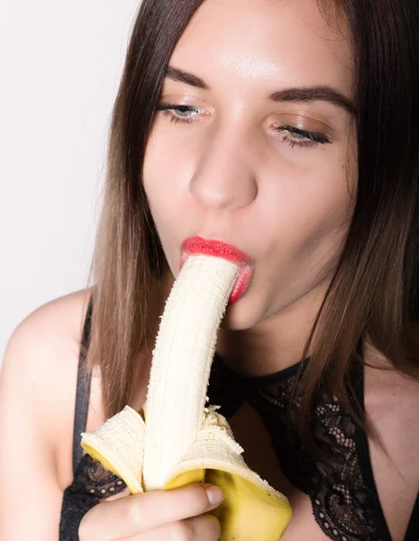 Jovem mulher espantada em lingerie rendada segurando uma banana, ela vai comer uma banana. ela chupa uma banana — Fotografia de Stock