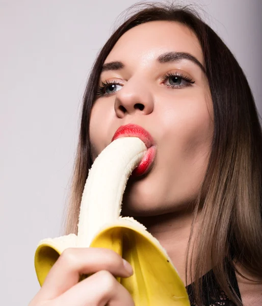 Młody zdumiony kobiety w bieliźnie koronkowy gospodarstwa banana, ona ma zamiar zjeść banana. ona ssie banana — Zdjęcie stockowe