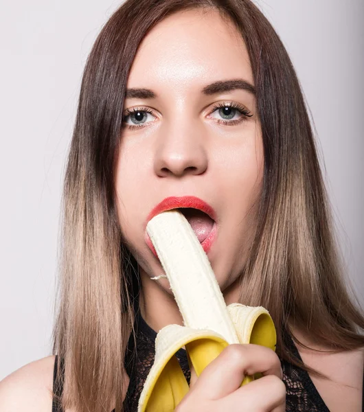 Joven mujer sorprendida en lencería de encaje sosteniendo un plátano, ella va a comer un plátano. chupa un plátano — Foto de Stock