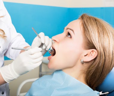 Resepsiyon kadın dişçideydi. Doktor diş çürümesi üzerine ağız boşluğu inceler. Çürükkoruması. Diş çürümesi tedavisi. Diş hekimi ofisinde diş kürkadın hasta