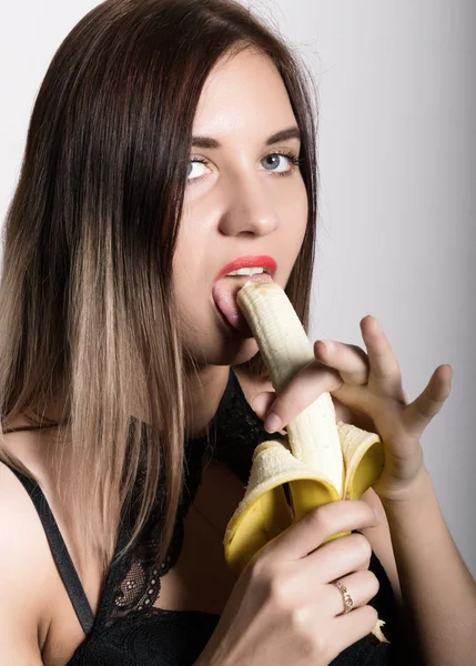 Joven mujer sorprendida en lencería de encaje sosteniendo un plátano, ella va a comer un plátano. chupa un plátano —  Fotos de Stock