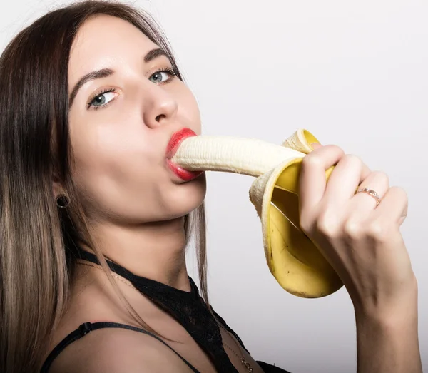 Joven mujer sorprendida en lencería de encaje sosteniendo un plátano, ella va a comer un plátano. chupa un plátano — Foto de Stock