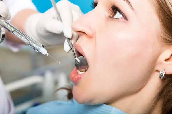 La recepción fue en el dentista femenino. El médico examina la cavidad oral en la caries dental. Protección contra caries. Tratamiento de caries dental. Paciente femenina en el consultorio del dentista curando dientes — Foto de Stock