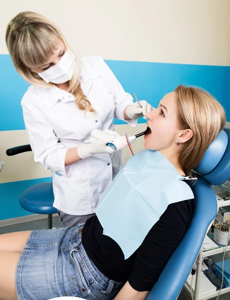 La recepción fue en el dentista femenino. El médico examina la cavidad oral en la caries dental. Protección contra caries. Tratamiento de caries dental. Paciente femenina en el consultorio del dentista curando dientes — Foto de Stock