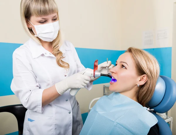The reception was at the female dentist. Doctor examines the oral cavity on tooth decay. Caries protection. Tooth decay treatment. Female patient at dentist office curing teeth — Stock Photo, Image