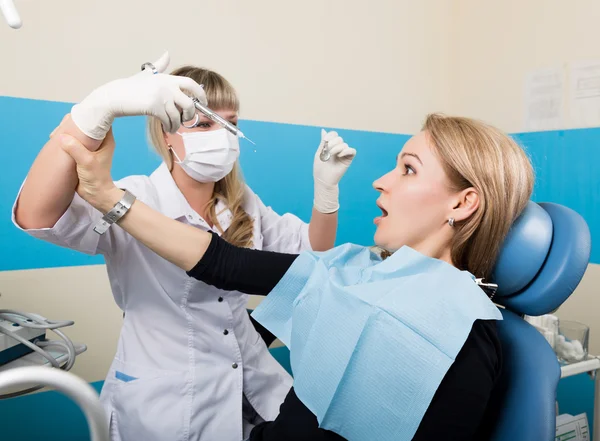 El médico examina la cavidad oral en la caries dental. Protección contra caries. Tratamiento de caries dental. El médico inyecta al paciente, el paciente toma la mano del médico y no le pone una inyección. — Foto de Stock