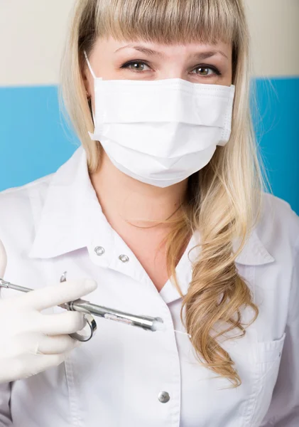 Mujer rubia dentista sosteniendo una jeringa en su mano para preparaciones inyectables — Foto de Stock