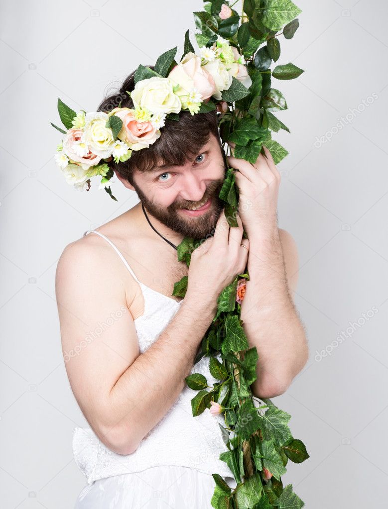 bearded man in a womans wedding dress on her naked body, clinging to the vine. on his head a wreath of flowers. funny bearded bride