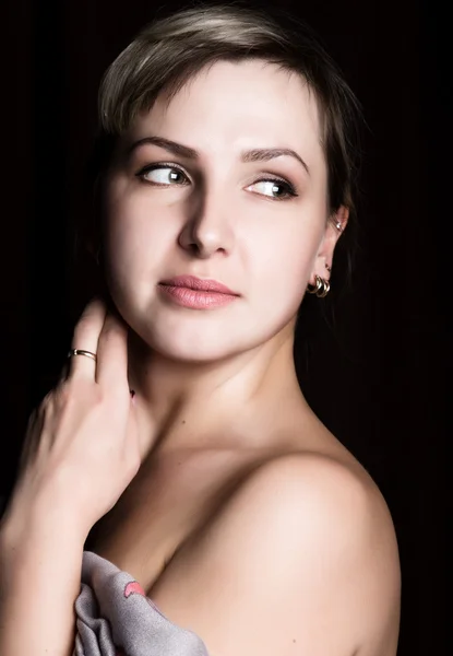 Close-up retrato de uma mulher bonita com ombros nus em um fundo escuro — Fotografia de Stock