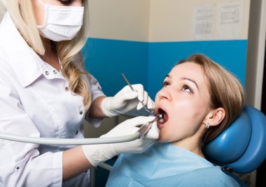 Resepsiyon kadın dişçide yapıldı. Doktor diş çürüğü sözlü den inceliyor. Çürük koruması. Doktor hasta bir anestezik enjeksiyon koyar.