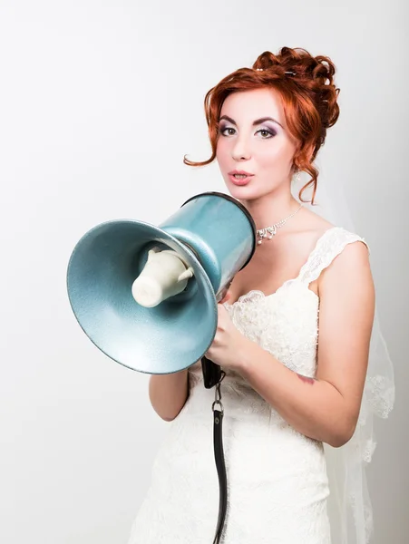 Hermosa novia en un vestido de novia con un maquillaje de boda y peinado, ella grita en un megáfono. Relaciones públicas — Foto de Stock