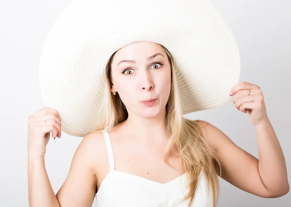 Hermosa mujer rubia divertida joven en camiseta blanca y un gran sombrero blanco sonriendo y posa caras — Foto de Stock