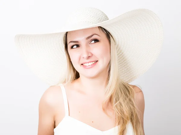 Hermosa mujer rubia divertida joven en camiseta blanca y un gran sombrero blanco sonriendo — Foto de Stock