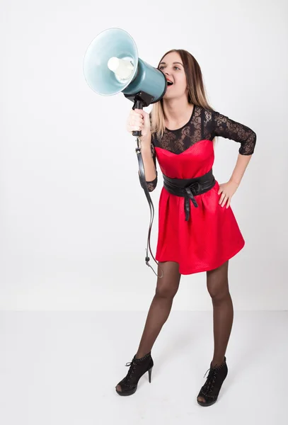 Chica hermosa piernas largas en un vestido rojo con mangas de encaje, ella grita en un megáfono. Relaciones públicas — Foto de Stock