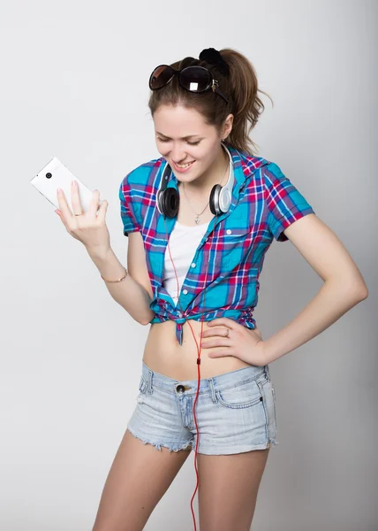 Девушка-подросток в джинсовых шортах и клетчатой рубашке разговаривает по мобильному телефону и выражает различные эмоции — стоковое фото