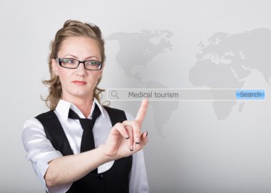Medikal turizm arama çubuğuna sanal ekran üzerinde yazılı. Internet teknolojileri iş ve ev. kadın takım elbise ve kravat, sanal bir ekranda bir parmak basar