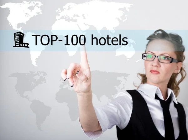 Top 100 hoteles escritos en una pantalla virtual. Tecnologías de Internet en negocios y turismo. mujer en traje de negocios y corbata, presiona un dedo en una pantalla virtual — Foto de Stock