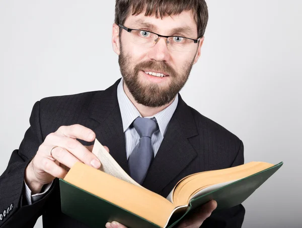Бородатый бизнесмен в деловом костюме и галстуке, читающий толстую книгу — стоковое фото