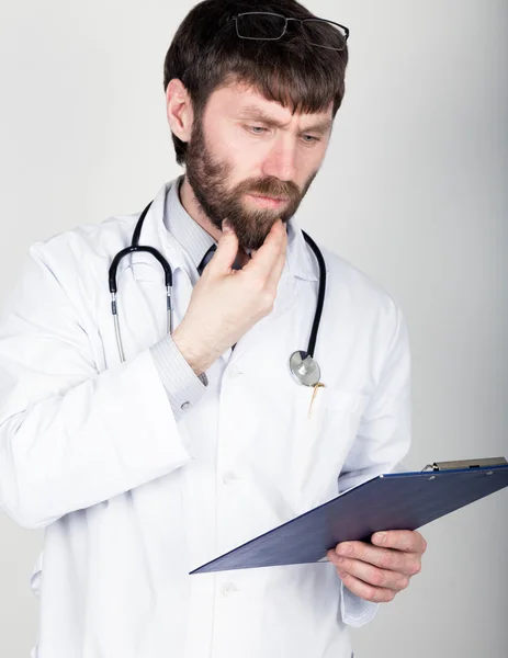 Közeli Portret egy orvos, aki egy Térkép-a jegyzet, sztetoszkóp a nyakába. Ő súrolja az állát. különböző érzelmek — Stock Fotó