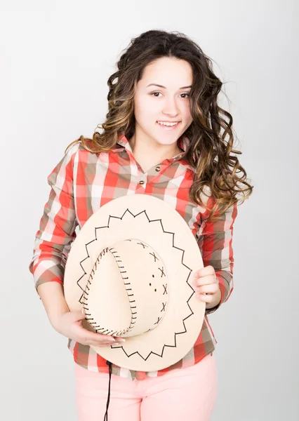 Beautiful curly girl in pink pants, a plaid shirt and cowboy hat. — ストック写真