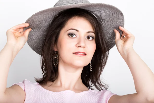 Hermosa joven morena sosteniendo un sombrero de ala ancha, esconde su cara detrás de un sombrero. concepto de chica coqueteando. expresión de diferentes emociones — Foto de Stock