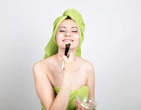 Gyönyörű fiatal nő öltözve egy törölköző teszi a kozmetikai maszk az arcon. szépség ipar és hazai bőr care koncepciót — Stock Fotó