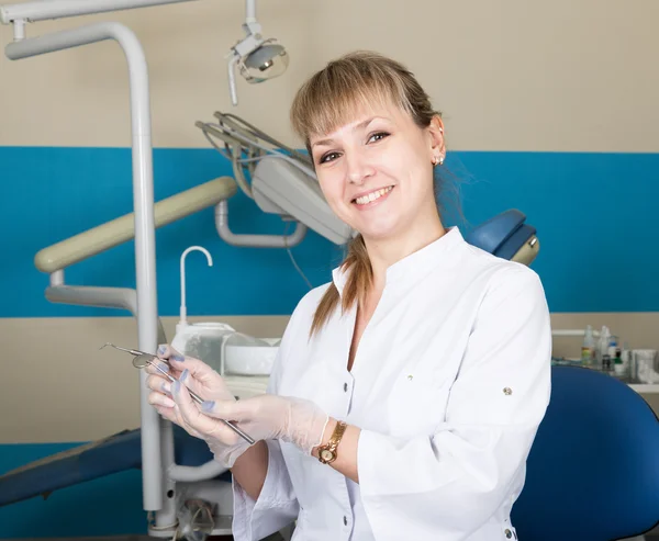Tıbbi alet tutan güzel sarışın kadın dişçi. içinde belgili tanımlık geçmiş diş ekipman — Stok fotoğraf