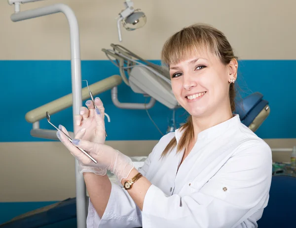 Tıbbi alet tutan güzel sarışın kadın dişçi. içinde belgili tanımlık geçmiş diş ekipman — Stok fotoğraf