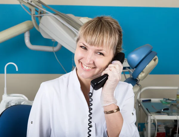 Адміністратор стоматологічної клініки, що тримає телефон, записи пацієнтів на прийомі — стокове фото
