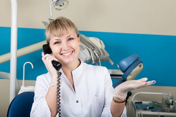 Адміністратор стоматологічної клініки, що тримає телефон, записи пацієнтів на прийомі — стокове фото